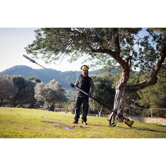 Worker holding an extended  DEWALT 54V XR FLEXVOLT 4.0 m 30 cm Pole Saw 