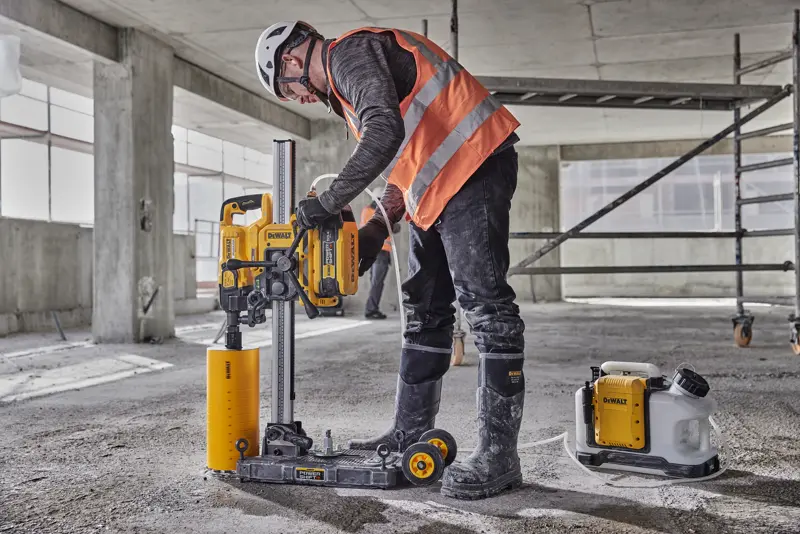 Arbeiter nutzt DEWALT DCPS151 Betonbohrmaschine auf Baustelle, mit Schutzausrüstung und Helm.