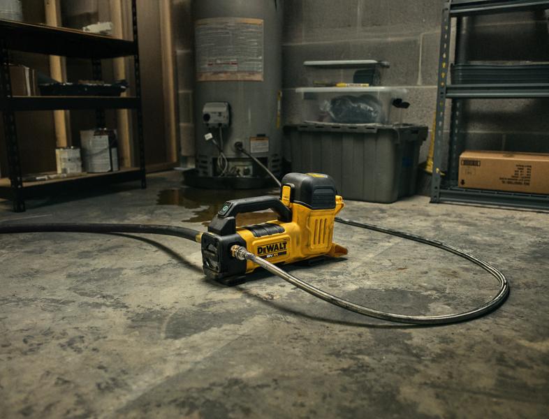 DEWALT DCE050N Fotografie-Werkzeug auf Werkstattboden, mit Schlauch, umgeben von Regalen.